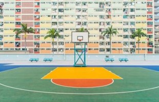 Empty basketball court in front of block of apartments.