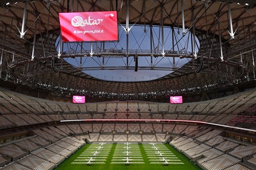 Image of empty stadium with a big screen showing a message saying Qatar See you in 2022