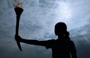 Silhouette of a female holding the olympic torch.